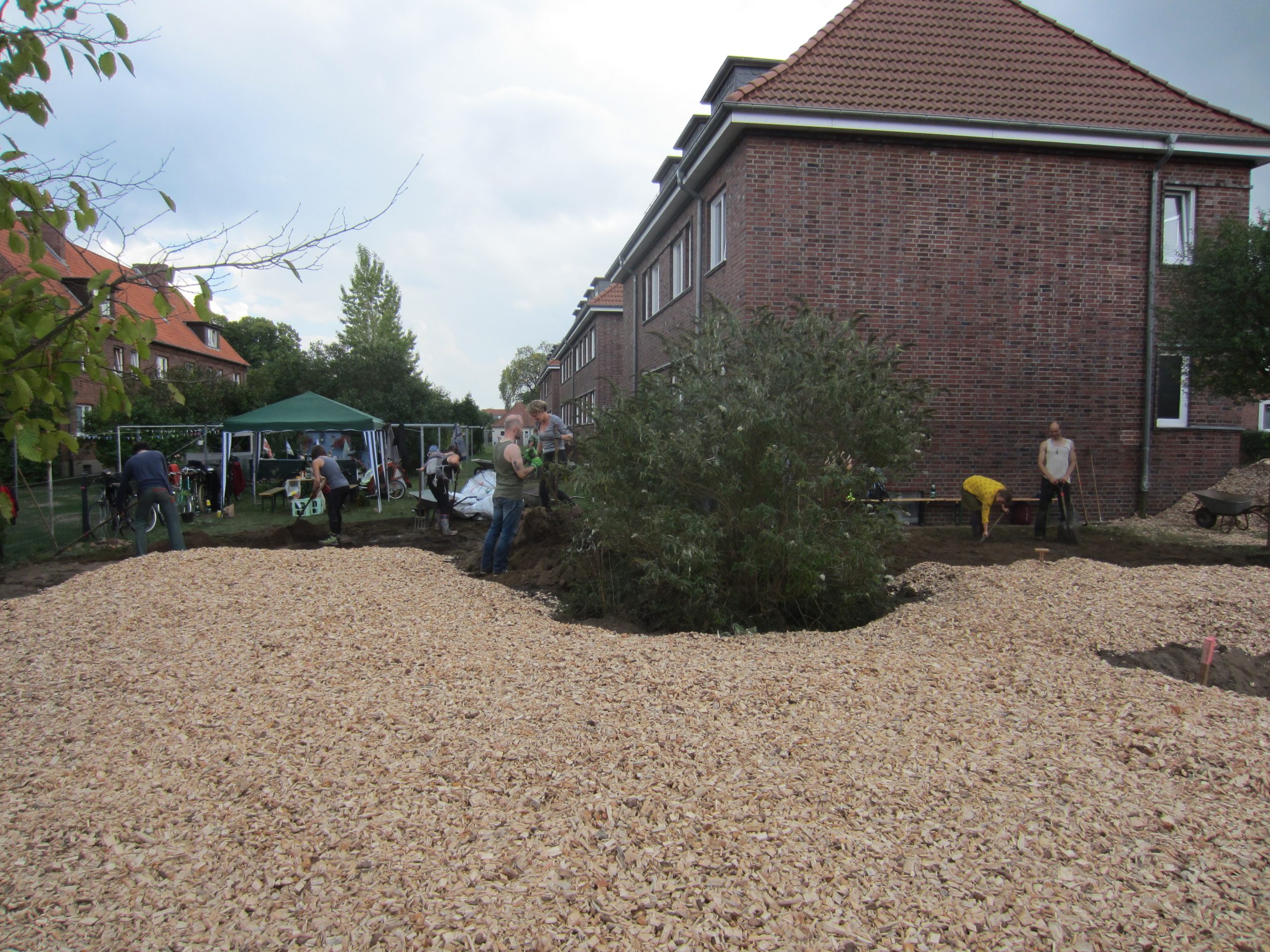 Das Bild zeigt eine mit Hackschnitzeln ausgelegte Fläche in einem Wohngebiet.